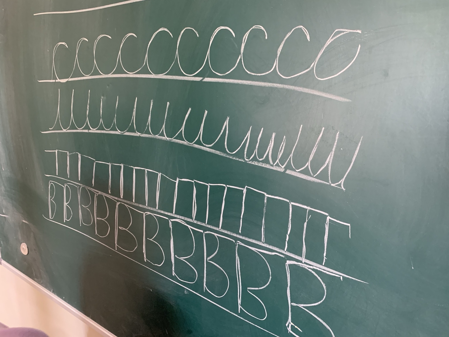 Chalkboard with rows of loops, lines, and letter forms used during a learning session